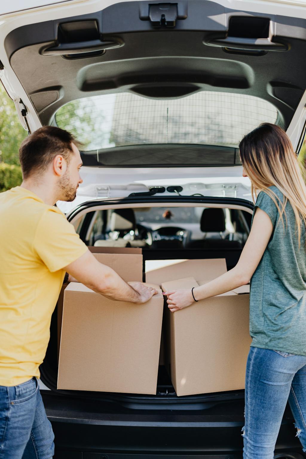 Couple putting carton boxes in car trunk